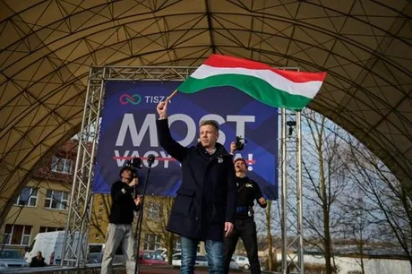 Un bărbat ținând steagul Ungariei pe o scenă electorală.