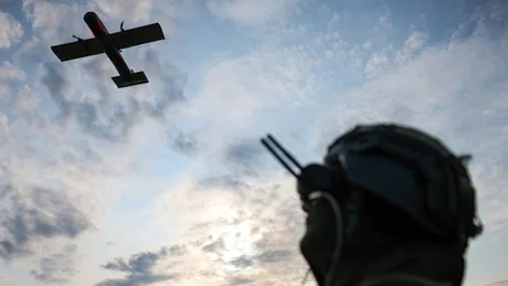 Drone ucrainene zburând deasupra unui soldat pe câmpul de luptă.