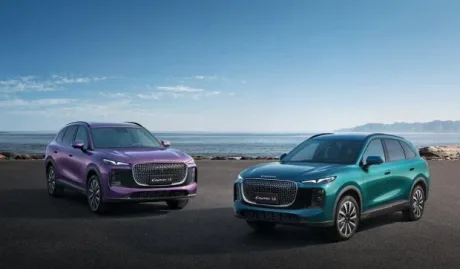 Două modele auto LEPAS expuse pe malul mării, cu un peisaj urban în fundal.