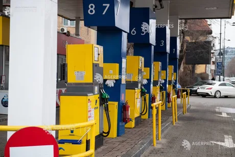 Stație de alimentare cu carburanți, cu pompe și mașini parcate.