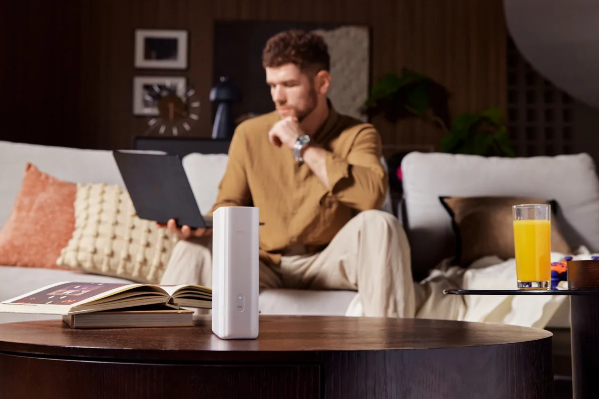 Utilizator lucrând pe laptop, cu TCL 5G CPE B50 în prim-plan.