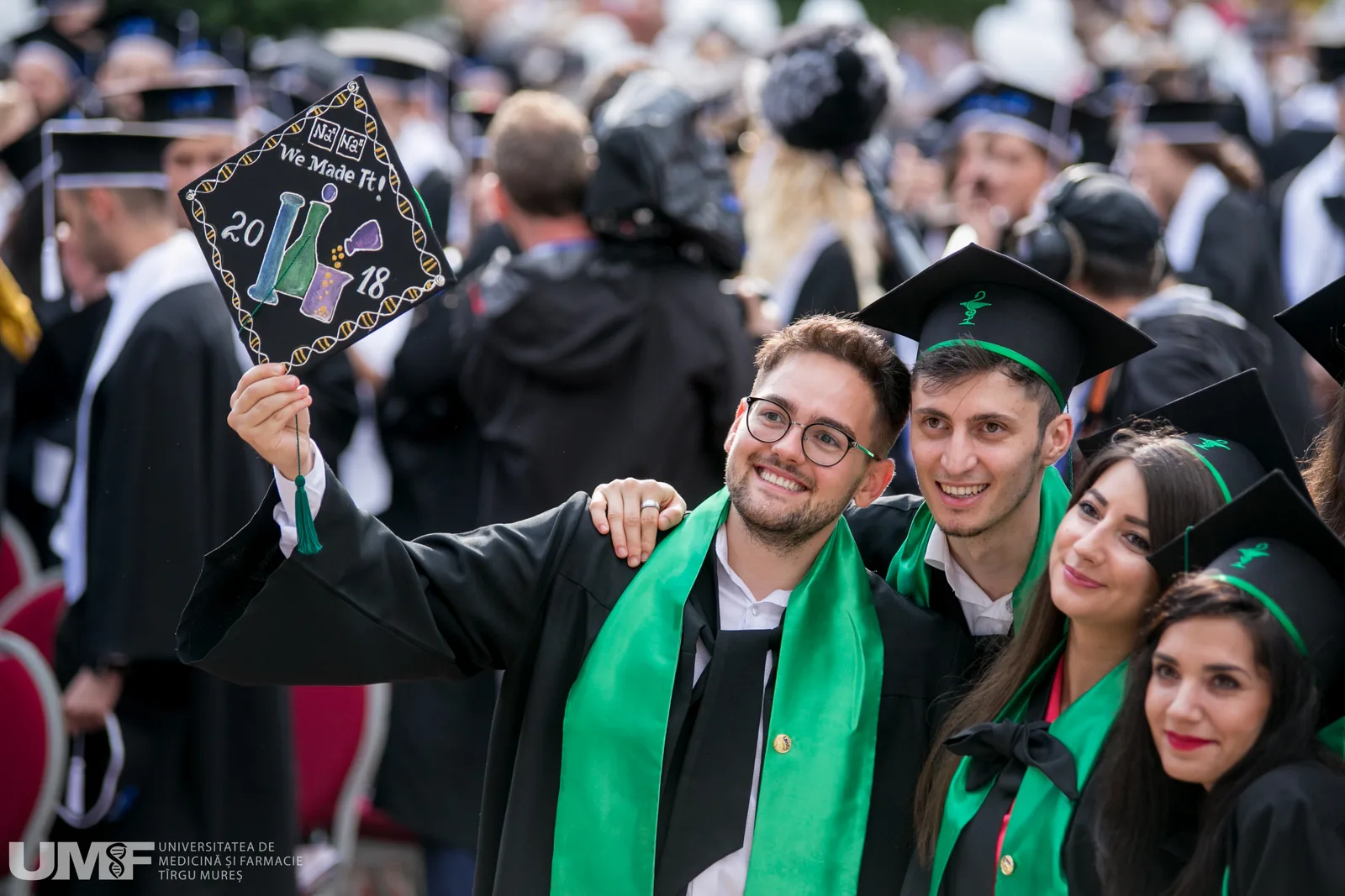 Absolvenți de medicină sărbătorind la ceremonia de absolvire, cu diplome în mână.
