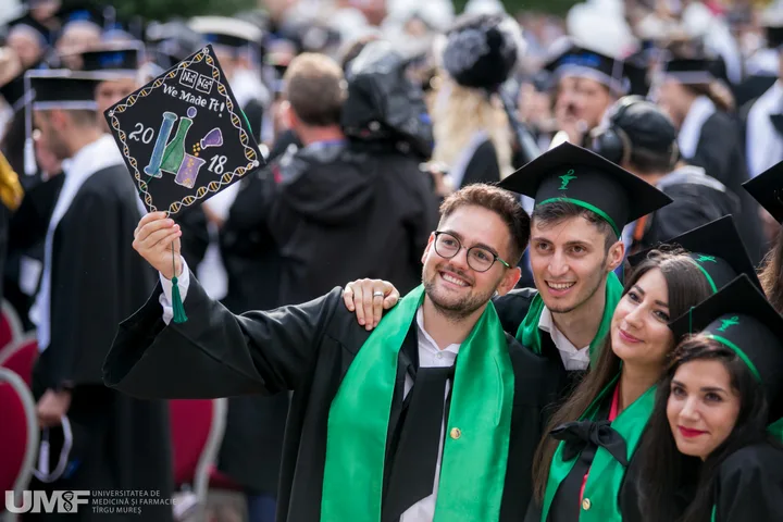 Absolvenți de medicină sărbătorind la ceremonia de absolvire, cu diplome în mână.