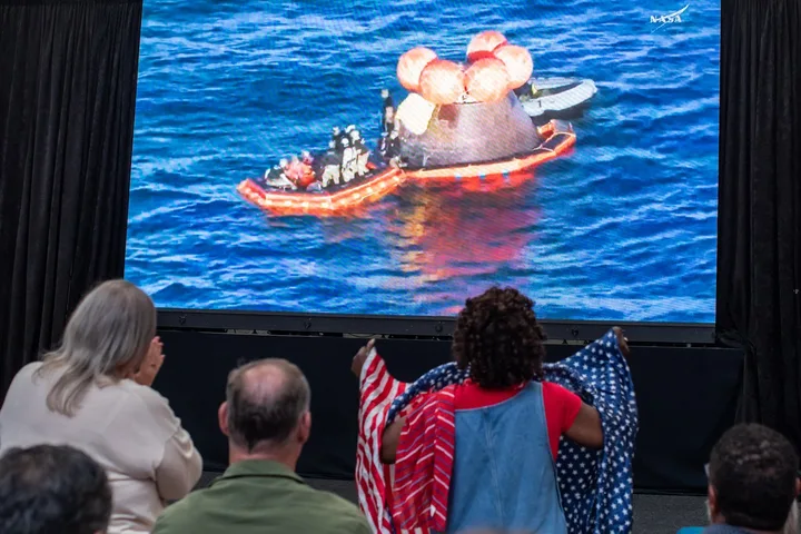 Spectatori aplaudă revenirea capsulei Orion în Oceanul Pacific.