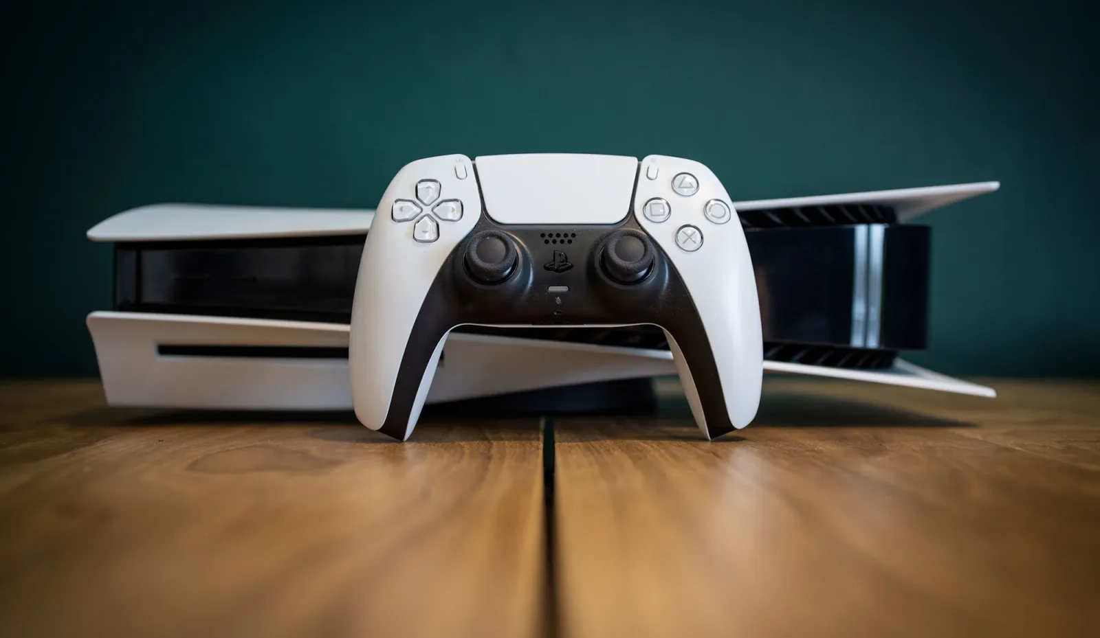 Console PlayStation 5 și controller pe un fundal de lemn.