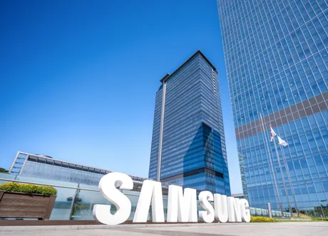 Clădire modernă Samsung cu logo mare pe fațadă, sub cer senin.