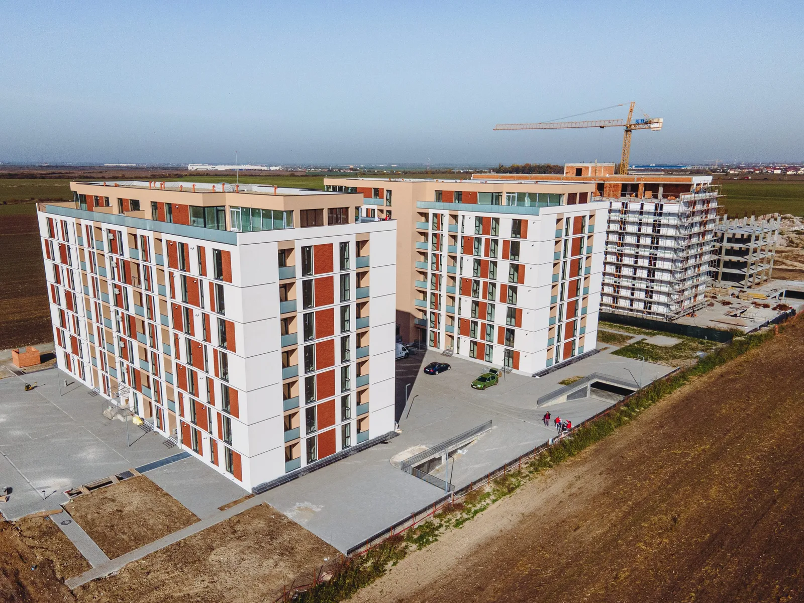 Blocuri de locuințe moderne în construcție, cu terenuri în jur.