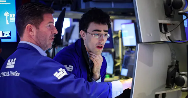 Investitori pe Wall Street discutând despre piețele financiare și perspectivele economice.