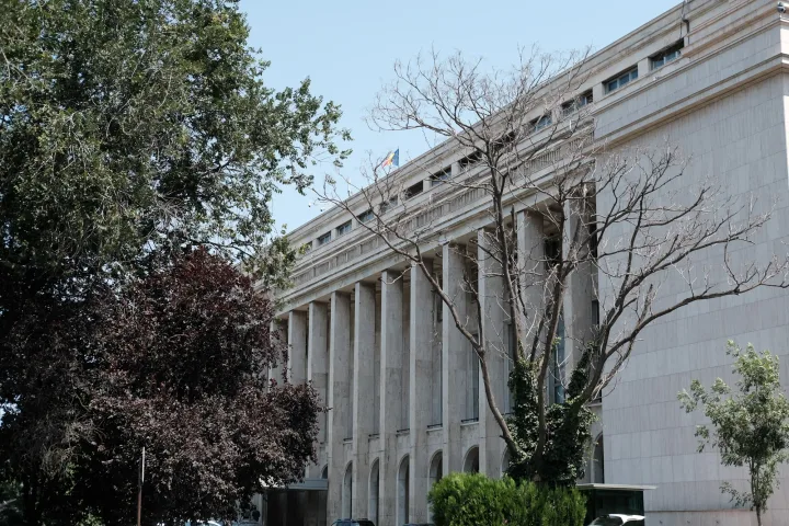 Clădirea Guvernului României, cu arbori în față, într-o zi senină.