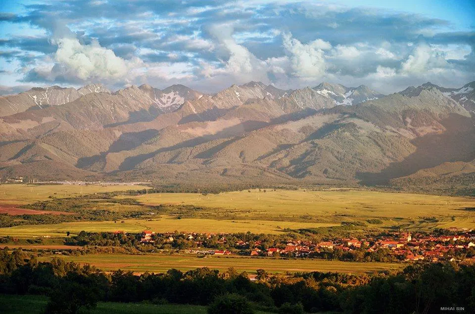 Peisaj montan cu văi verzi și sate pitorești în fundal.