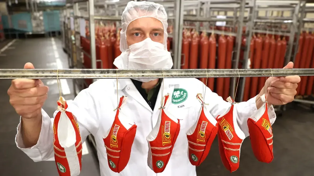 Un angajat prezintă cârnați într-o fabrică din Germania.