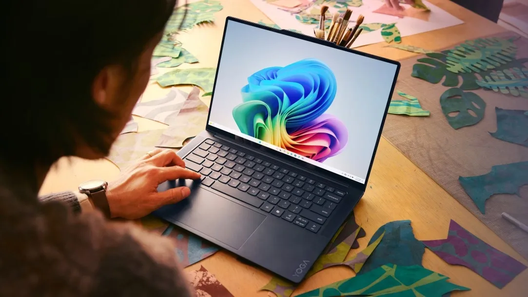 Utilizator lucrând pe un laptop cu Windows 11, înconjurat de materiale creative.