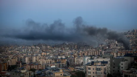Fum negru se ridică deasupra unui oraș dens populat, semn al unor atacuri recente.