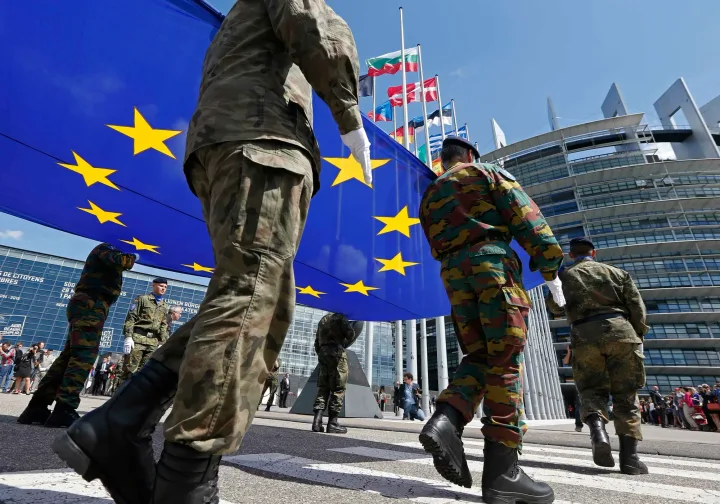 Soldați purtând steagul Uniunii Europene în fața clădirii Parlamentului European.