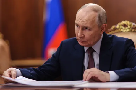 Vladimir Putin analizând documente într-un birou oficial.