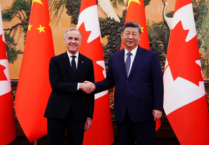Mark Carney și liderul chinez se strâng mâna în fața steagurilor naționale.