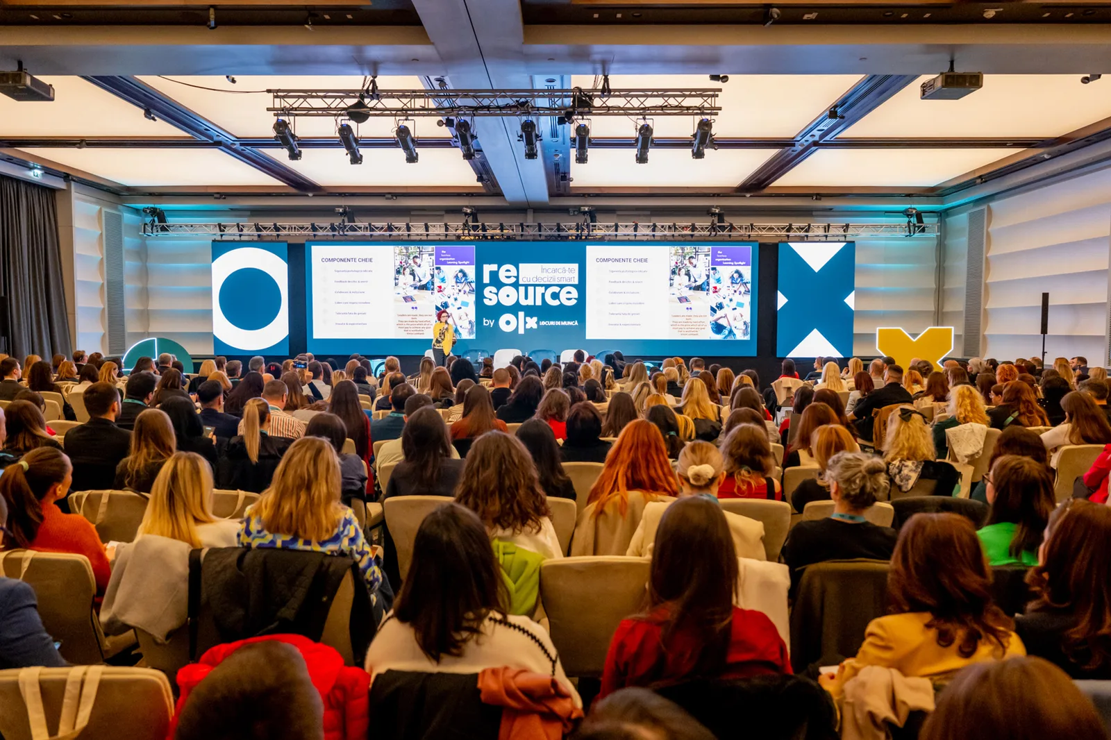 Eveniment OLX Group cu participanți numeroși, prezentări pe scenă.
