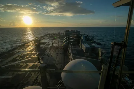 Nava de asalt amfibie Tripoli navigând pe marea calmă la apus.