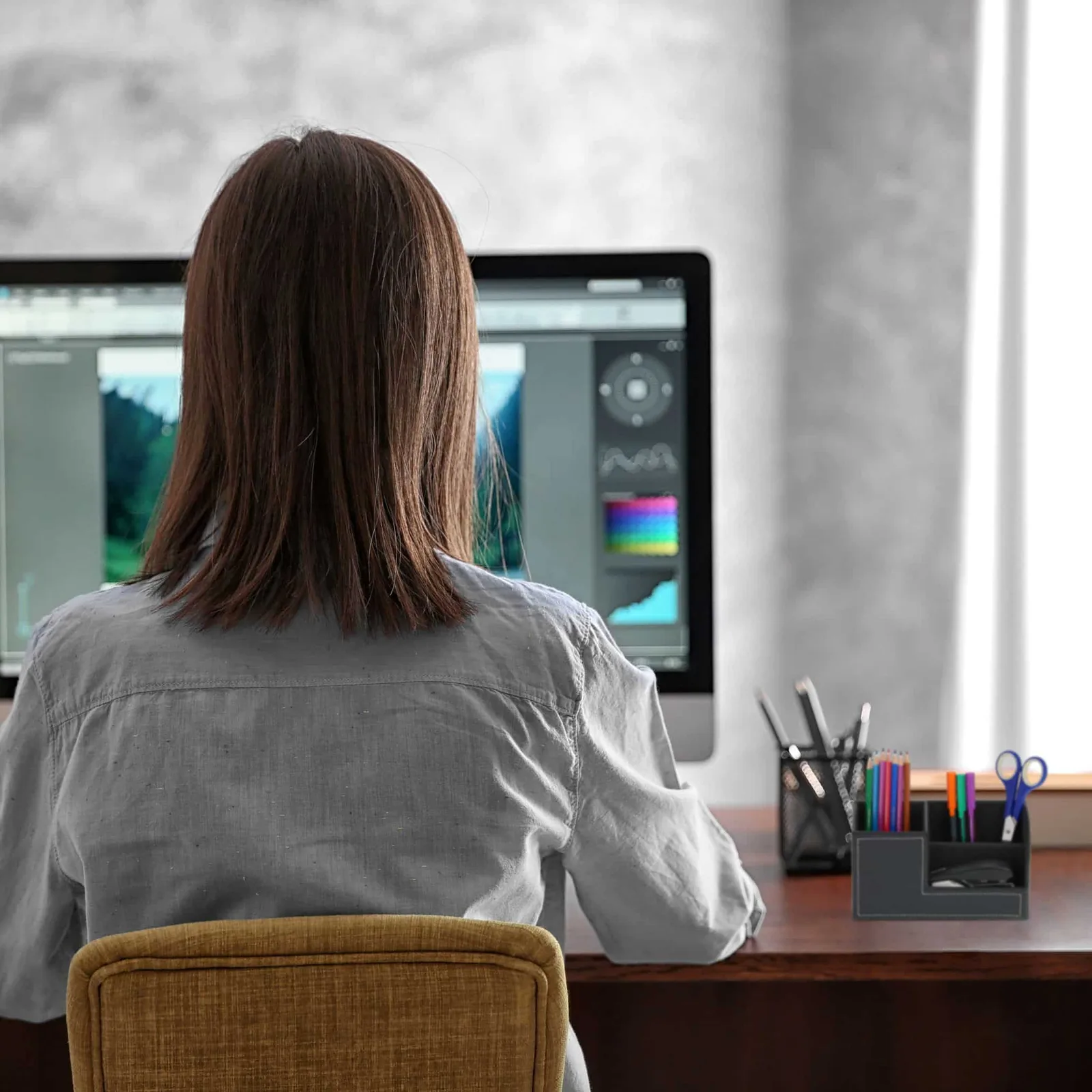 Angajat lucrând la birou, cu un monitor și un birou organizat.