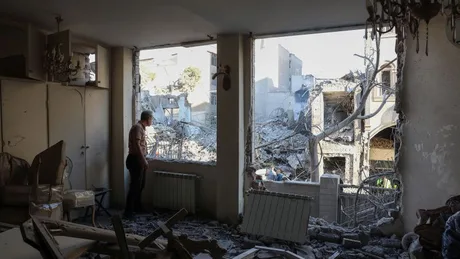 Un bărbat observă distrugerea dintr-o clădire afectată de război.