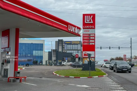Stație de benzină Lukoil cu prețuri afișate și mașini parcate.