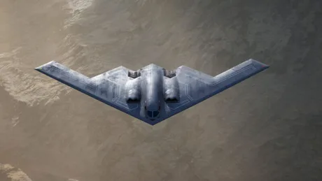 Bombardierul stealth B-21 Raider zburând deasupra unui peisaj montan.