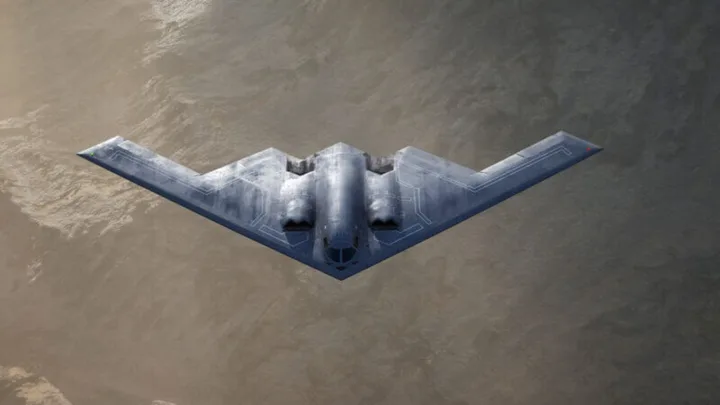 Bombardierul stealth B-21 Raider zburând deasupra unui peisaj montan.