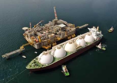 Vapor de transport LNG ancorat lângă platformă de extracție în mare.