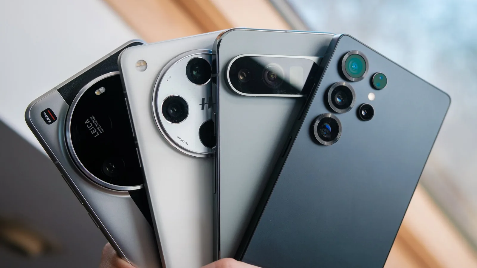 Patru smartphone-uri cu design modern și camere avansate, expuse pe o masă.