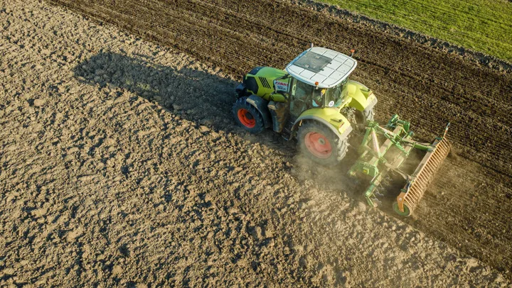 Tractor lucrând pe un câmp pregătit pentru semănat.