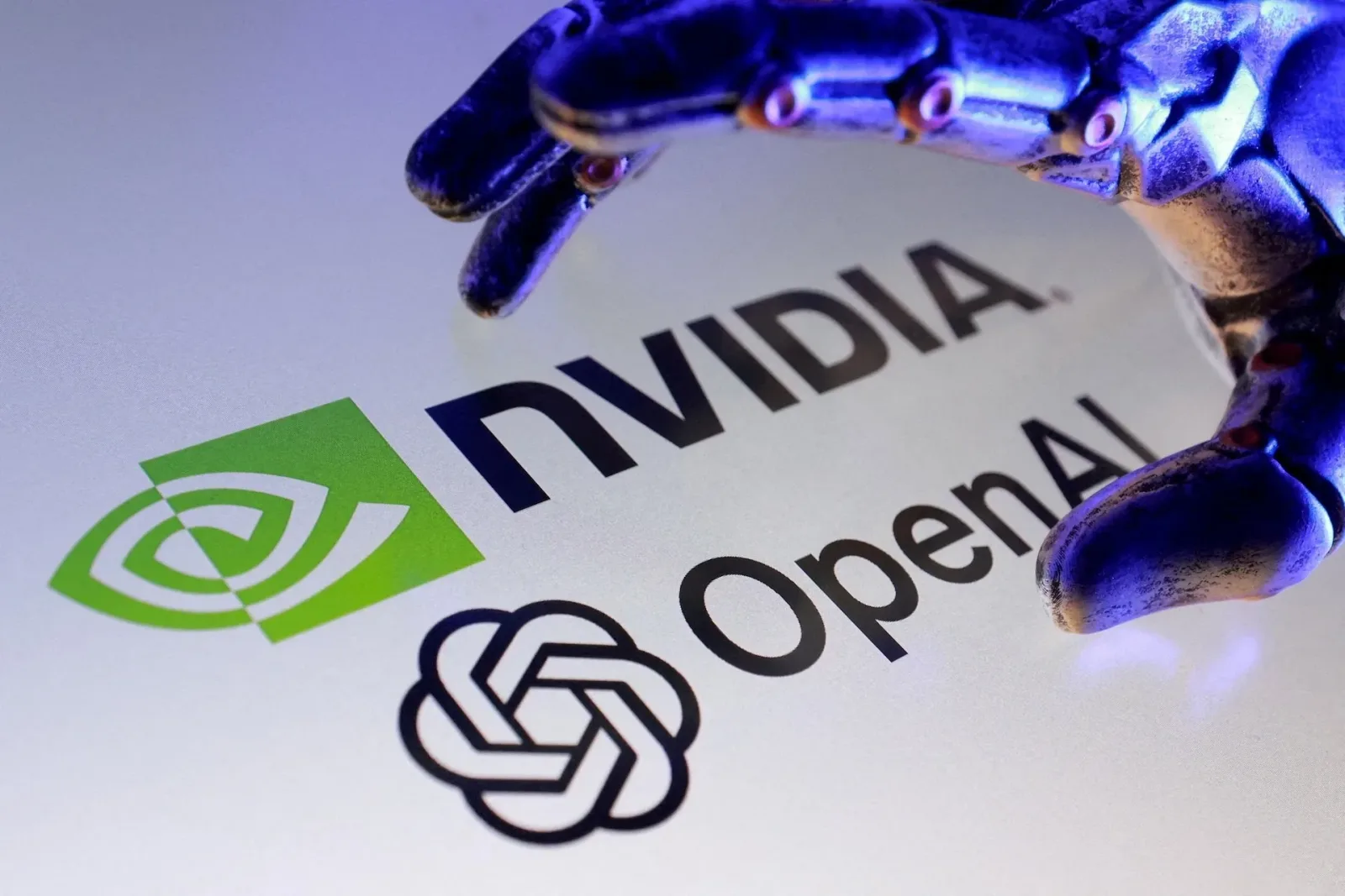Mână robotică interacționând cu logo-urile Nvidia și OpenAI.