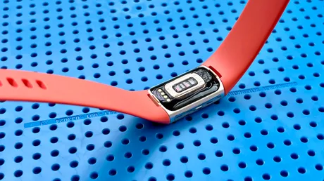 Brățară de fitness Fitbit pe un fundal albastru cu găuri.