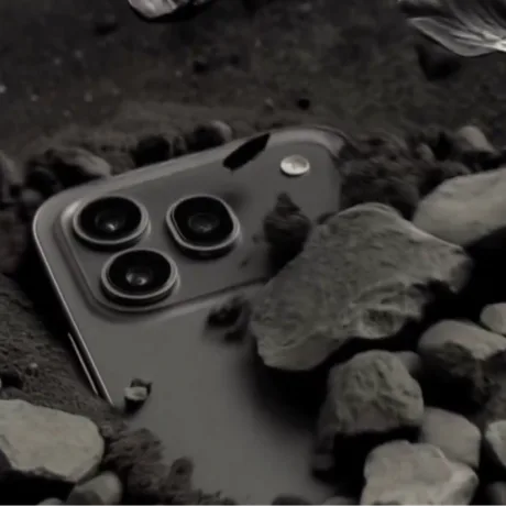 Un telefon HONOR îngropat în pietriș, evidențiind designul său modern.