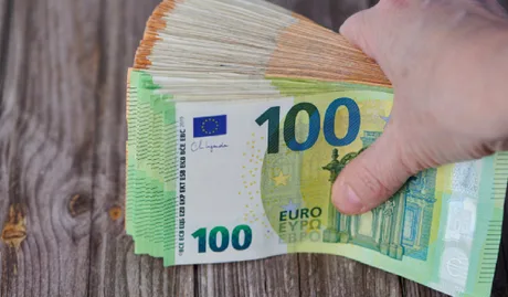 Bancnote de euro aranjate pe o masă din lemn.