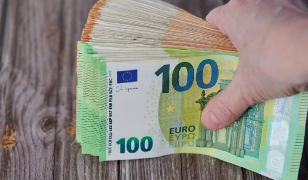 Bancnote de euro aranjate pe o masă din lemn.