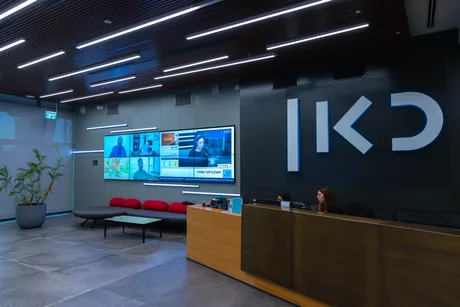 Recepția televiziunii publice KAN, cu ecrane informative și personal la birou.
