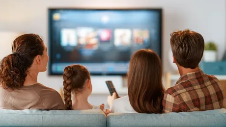 Familie urmărind un film pe televizor, bucurându-se de timpul petrecut împreună.