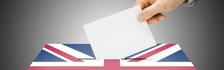 O mână introduce un buletin de vot într-o urnă cu steagul Marii Britanii.