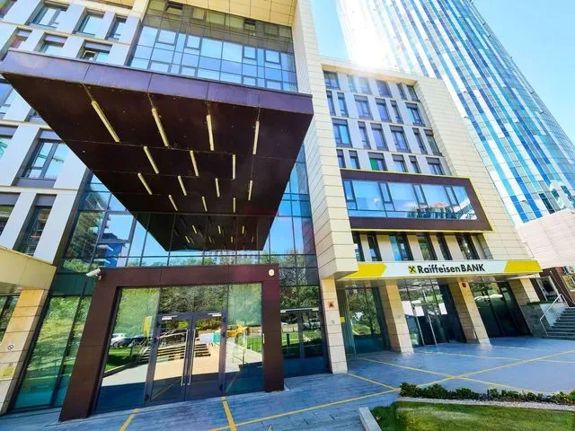 Clădire modernă a Raiffeisen Bank în București, cu feronerie galbenă distinctivă.