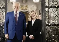 Două persoane zâmbind în fața unei uși ornate.