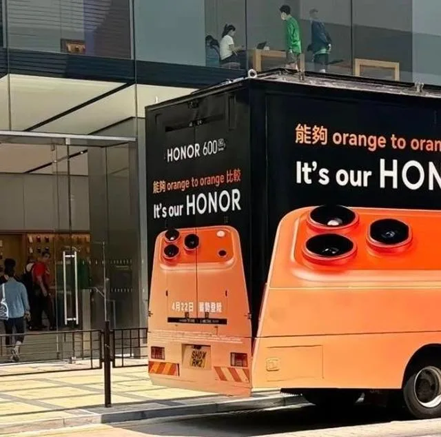 Reclamă ironică Honor pe un camion, comparând designul cu iPhone 17 Pro.
