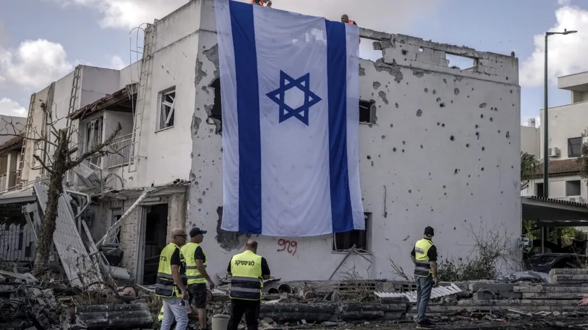 O clădire distrusă cu steagul Israelului atârnat pe fațadă.