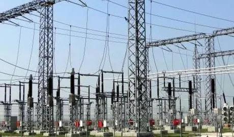 Rețea electrică cu stâlpi și cabluri în peisaj urban.