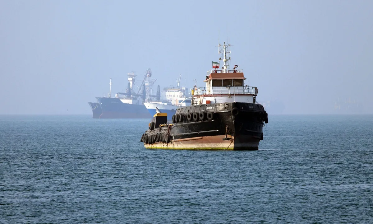 Vapor maritim navigând pe ape calme, cu nave în fundal.