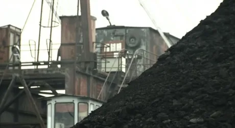 Peisaj industrial cu echipamente miniere și stocuri de cărbune în Valea Jiului.