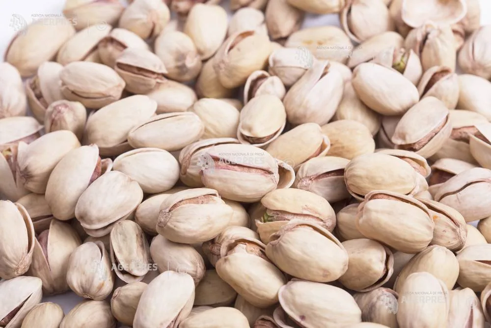 Fistic proaspăt, cu coajă deschisă, pe un fundal alb.