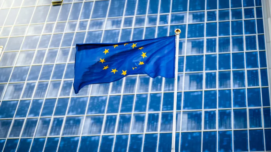 Steagul Uniunii Europene fluturând în fața unei clădiri moderne.