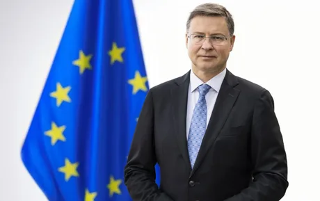 Valdis Dombrovskis, comisar european, în fața steagului Uniunii Europene.