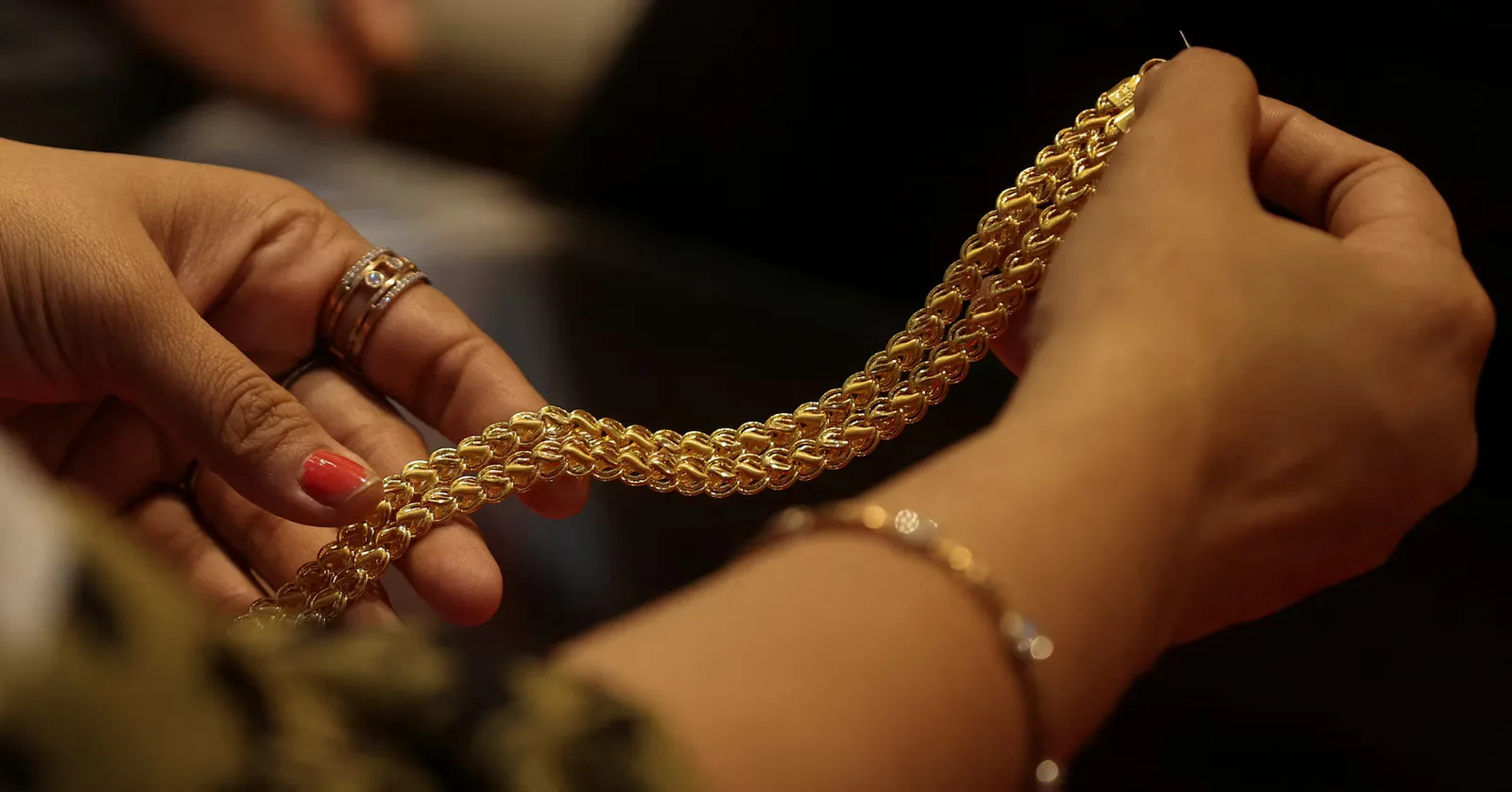 O persoană examinează o brățară din aur strălucitor.