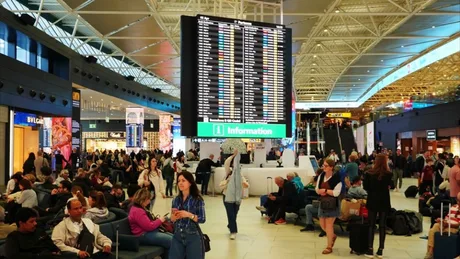 Aeroport aglomerat, pasageri așteptând zboruri internaționale.